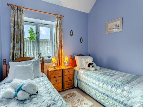 two beds in a bedroom with two teddy bears on them at Nightingale in Temple Combe