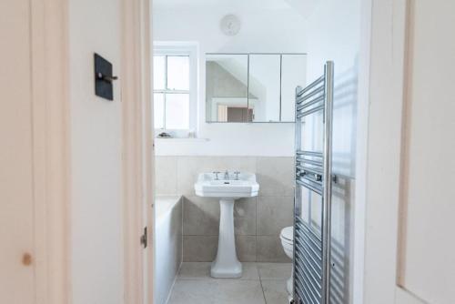 Baño blanco con lavabo y espejo en Stunning Flat in Highbury Hill, en Londres