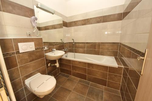 a bathroom with a toilet and a sink and a tub at Hotel U Tří hrušek suites & apartments in České Budějovice