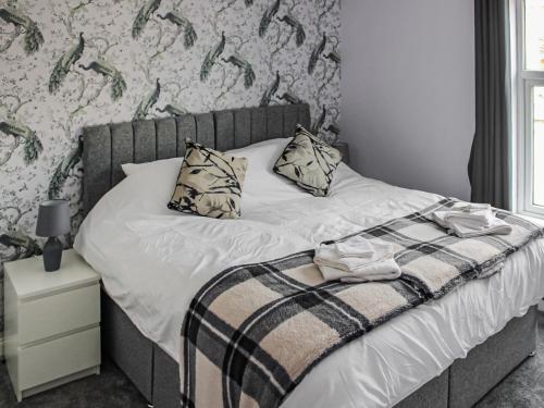 Una cama con manta y almohadas. en Sandy Paws en Gorleston-on-Sea