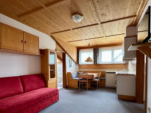 a living room with a red couch and a kitchen at B&B Apartments Haus Gasser in Monguelfo