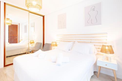 een witte slaapkamer met een groot wit bed en een spiegel bij Apartamento Cimadevilla II in Gijón