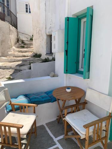 un patio con 2 sillas, una mesa y una ventana en Vera's traditional house - Chora, en Serifos Chora