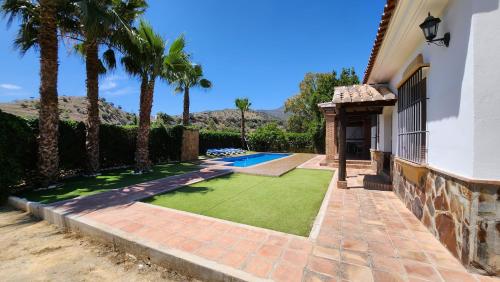 a backyard with a lawn and a swimming pool at CASA PEPE Y MARI CON PISCINA in Alora