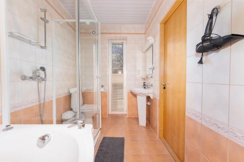 La salle de bains est pourvue d'une douche, d'un lavabo et d'une baignoire. dans l'établissement VäeVilla, à Otepää
