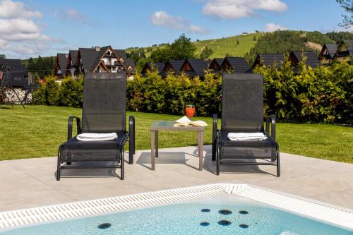 two chairs and a table next to a pool at Willa Skałka in Białka Tatrzanska