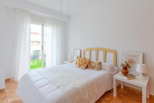 a white bedroom with a white bed and a window at Tiny Tranquility by Fidalsa in Torrevieja