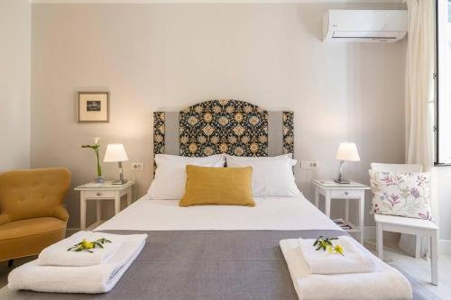 ein Schlafzimmer mit einem großen Bett mit zwei Tischen und einem Stuhl in der Unterkunft Palazzino Leone - Corfu Old Town Liston Deluxe Apartment in Korfu-Stadt