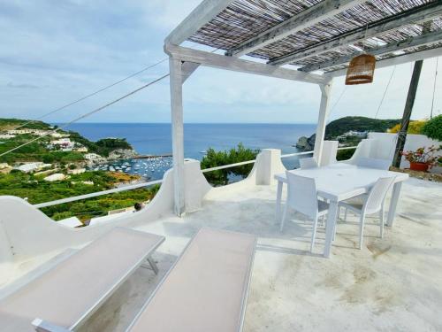 einen weißen Tisch und Stühle auf einem Balkon mit Meerblick in der Unterkunft Maridea - Vela in Ponza