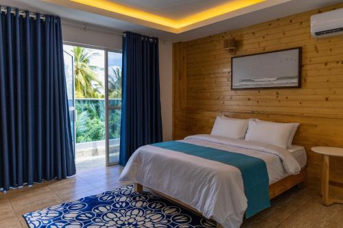 Surf House by Konalle في Gaafu Dhaalu Atoll: غرفة نوم بسرير مع جدار خشبي