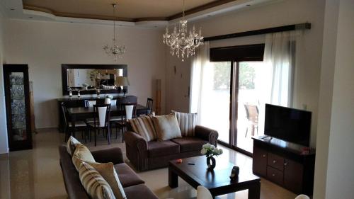 a living room with a couch and a tv and a table at Kos Villa - Family Comfort with large Garden, Jacuzzi in Kos