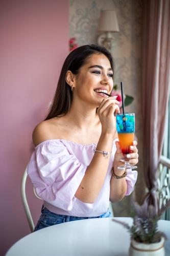 a woman sitting at a table drinking a drink at Garni Hotel Lotos in Niš