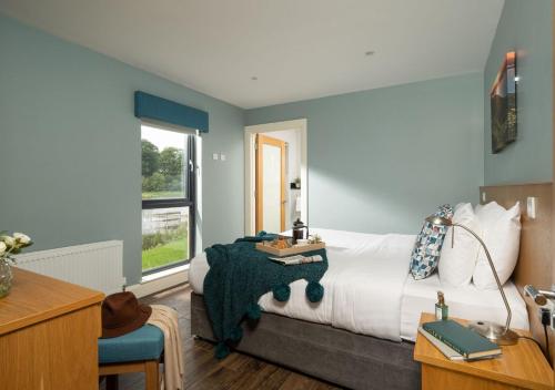 Schlafzimmer mit einem Bett, einem Schreibtisch und einem Fenster in der Unterkunft Killyhevlin Lakeside Hotel & Lodges in Enniskillen