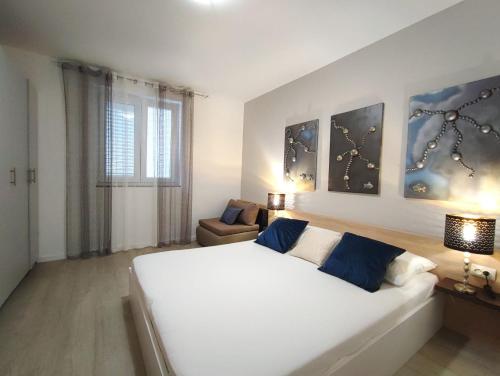 - une chambre avec un grand lit blanc et une chaise dans l'établissement Apartments Gavran 2., à Baška Voda