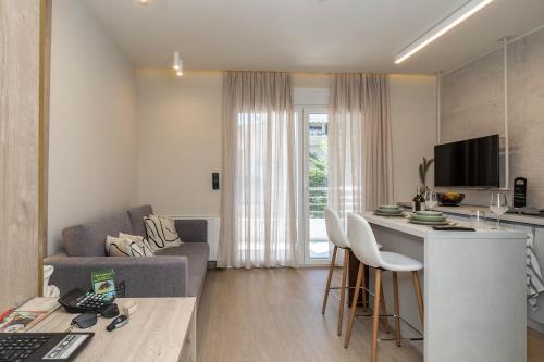 8 Blocks Apartments 4A في أليكساندروبولي: مطبخ وغرفة معيشة مع أريكة وطاولة