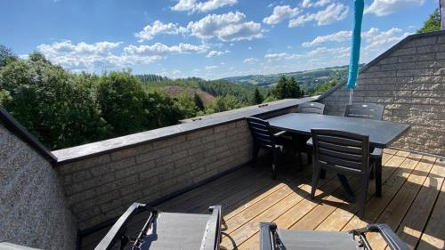 a patio with a table and chairs on a deck at TERRASSES DE MALMEDY- CHALET 108 Le Chalet du Cerf & TRIPLEX 223 Le Refuge du Cerf in Malmedy