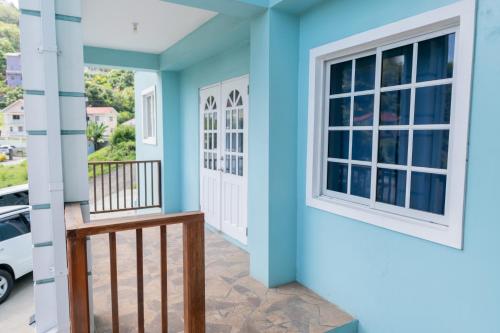 a house with blue walls and a balcony with a window at Golden Palms Apartment in Kingstown