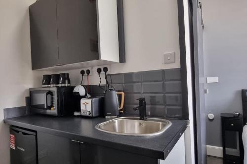 a kitchen counter with a sink and a microwave at Contemporary Studio Haven l 1Bed 1 Bath in London in London