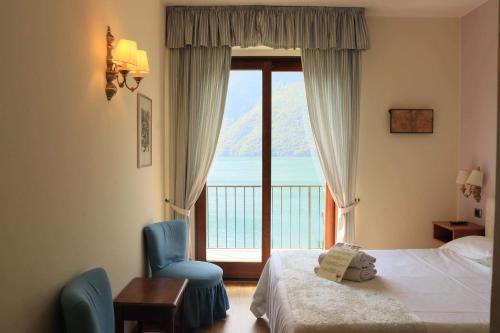 Habitación de hotel con cama y ventana con vistas. en Hotel Stella D'Italia, en Valsolda