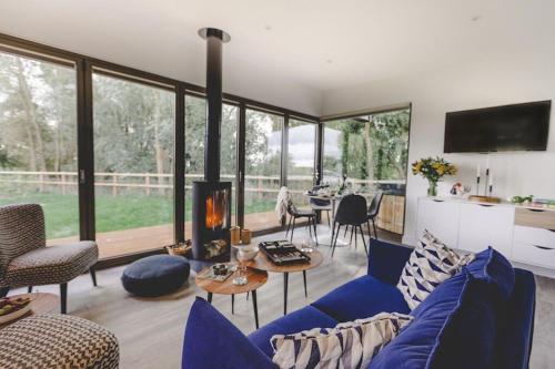 a living room with a blue couch and a fireplace at Eco Lodge "Deben" with Private Hot Tub in East Bergholt