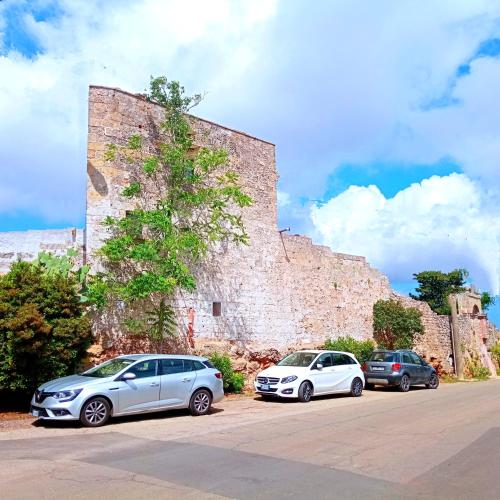 three cars parked in front of a stone wall at Masseria delle Rose 1760 in Alessano