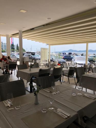 a restaurant with tables and chairs and cars in a parking lot at Šangulin Palace M in Biograd na Moru