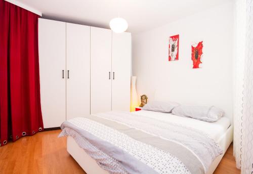 a bedroom with a white bed with a red curtain at Istriana Apartment in Piran