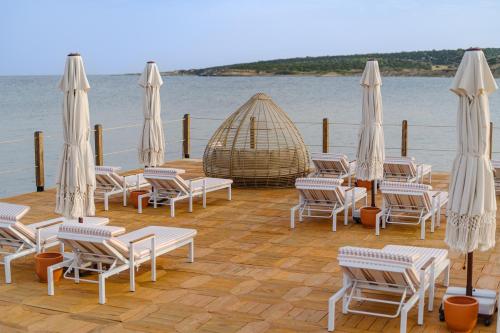 a group of chairs and umbrellas on a wooden deck at Blue Sea Karpasia Hotel in Rizokarpaso