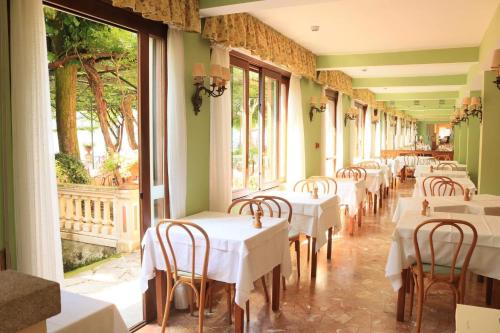 uma fila de mesas num restaurante com toalha de mesa branca em Hotel Stella D'Italia em Valsolda