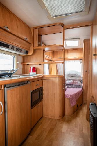 a small kitchen with wooden cabinets and a bed in it at Maszoperia Sun4hel Kite & Wind & Surf in Jastarnia
