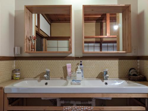 a bathroom with two sinks and two mirrors at Guesthouse Tomaru in Takayama