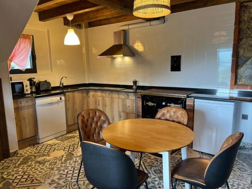 eine Küche mit einem Holztisch und Stühlen in der Unterkunft La Cabaña de La Nina in Beceña