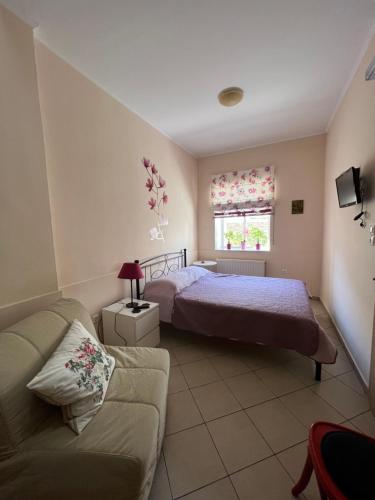 a bedroom with a bed and a couch and a window at Maria's guesthouse in Batsi