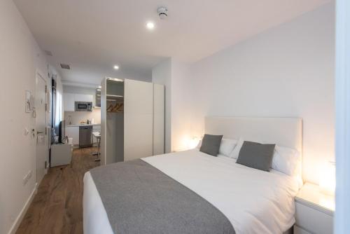 1 dormitorio con 1 cama blanca grande y cocina en Apartamentos Santa María 15, en Jerez de la Frontera