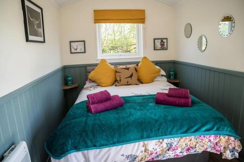 a bedroom with a bed with purple pillows on it at Close to Nature Easy to Find shepherd's hut in North Molton
