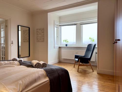 a bedroom with a bed and a chair and windows at One Bedroom Apartment In Glostrup, Tranemosevej 1, in Glostrup