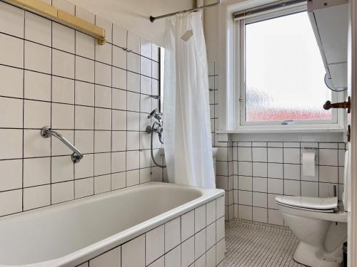 a bathroom with a tub and a toilet and a window at One Bedroom Apartment In Glostrup, Tranemosevej 1, in Glostrup