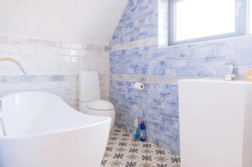 uma casa de banho com um WC branco e azulejos azuis em Lush & Spacious 3BD House - East Brighton em Brighton & Hove