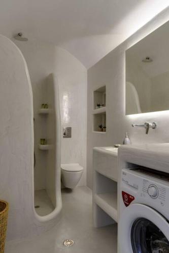 a white bathroom with a toilet and a washing machine at Sylvia's Villa in Imerovigli