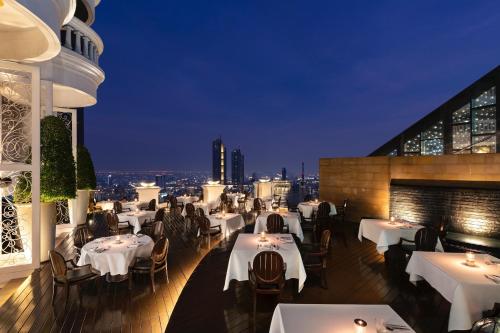 a restaurant with white tables and chairs on a balcony at night at lebua at State Tower in Bangkok