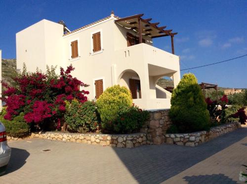 una casa blanca con algunos arbustos y flores en Hotels Kalimera Inn, en Elafonisos