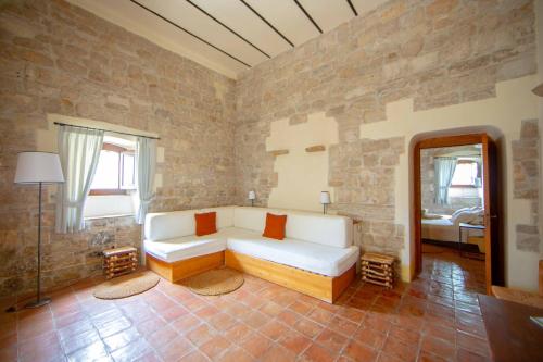 uma sala de estar com um sofá branco numa parede de tijolos em Lama Di Luna Biomasseria em Montegrosso