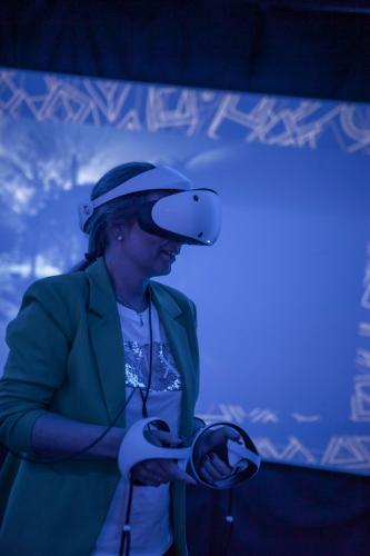 a woman wearing a hat is looking at a video game controller at Amenity Hotel & Resort Lipno in Lipno nad Vltavou