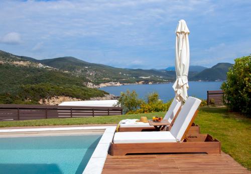 a pool with an umbrella and chairs next to a swimming pool at Zavia Resort in Syvota