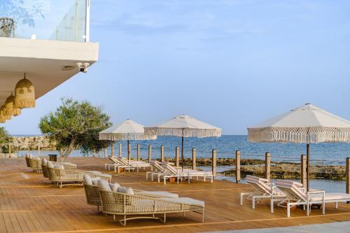 a deck with chairs and umbrellas on the beach at Blue Sea Karpasia Hotel in Rizokarpaso