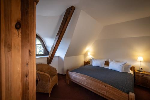 ein Schlafzimmer mit einem Bett und einem Stuhl in einem Zimmer in der Unterkunft Gutshof Bastorf in Kühlungsborn