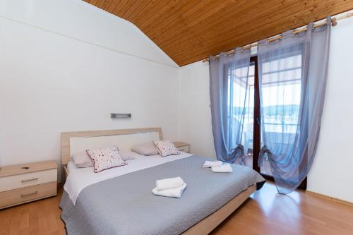 una camera da letto con un letto con cuscini rosa e una finestra di Apartments Luci a Rab