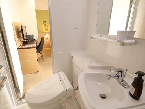 a white bathroom with a toilet and a sink at WeBase TAKAMATSU in Takamatsu
