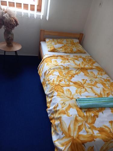 a bedroom with a bed with a yellow flower comforter at Guest House Visoko in Visoko