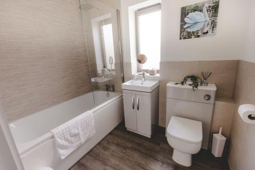 W łazience znajduje się toaleta, wanna i umywalka. w obiekcie Beautiful "Stour" Eco Lodge with Private Hot Tub w mieście East Bergholt